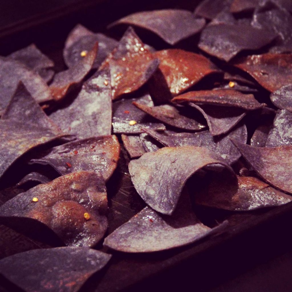 Blue corn chips, glistening majestically with pride and borrowed olive oil.
