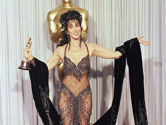 Cher shows off both her Oscar and Bob Mackie black-sequined gown after winning the award for best actress for her role as the superstitious young widow of "Moonstruck" at the 60th Annual Academy Awards, April 12, 1988 in Los Angeles. (AP Photo/Lennox McLendon)