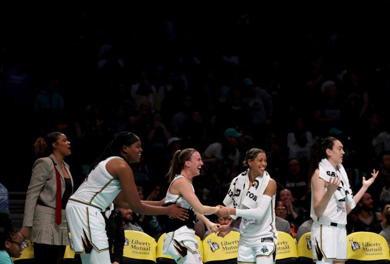 Nyara Sabally, Jonquel Jones, Sabrina Ionescu, Natasha Cloud, and Breanna Stewart, celebrate a teammate's shot from the bench.