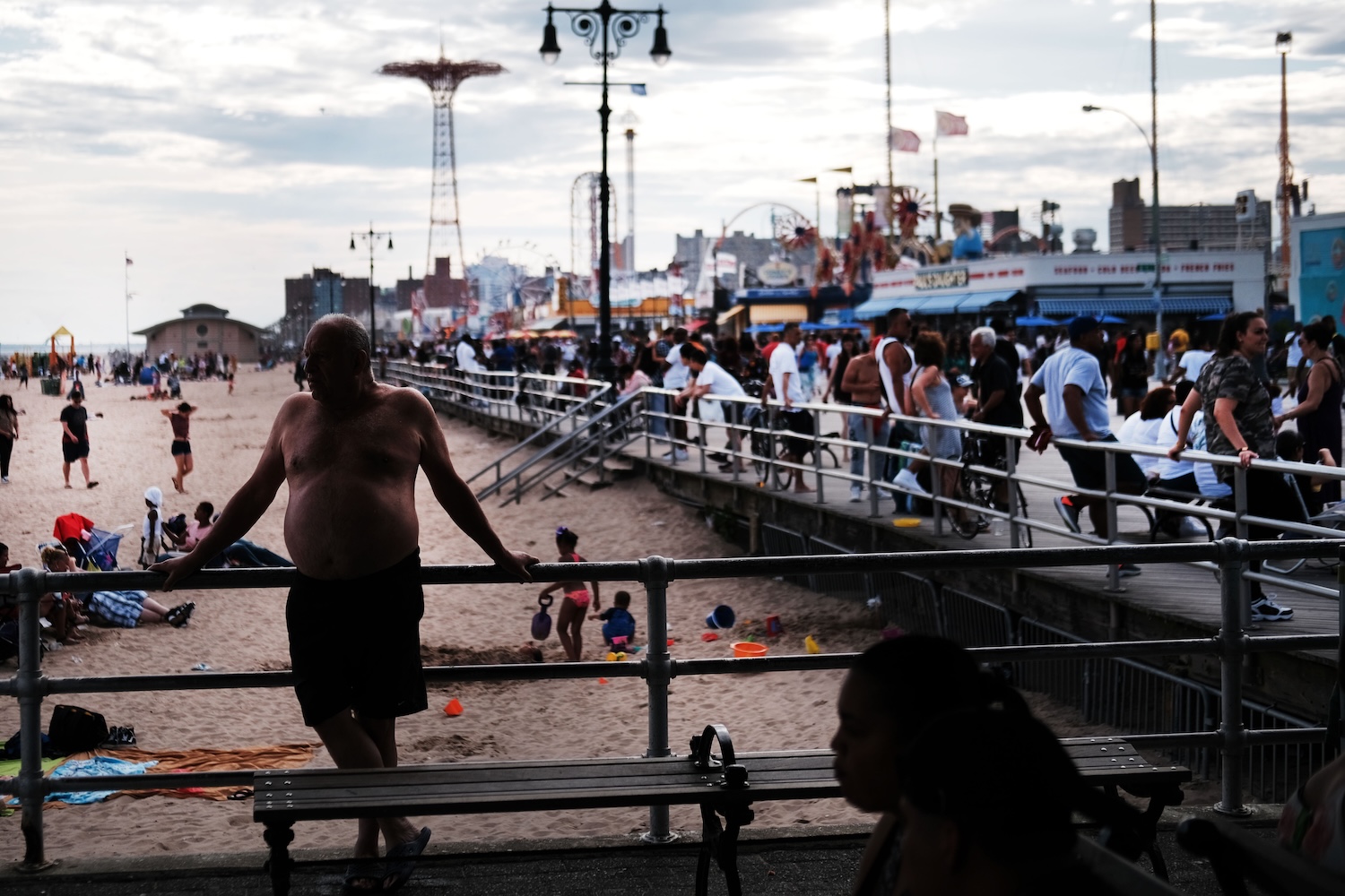 People gather along the Coney Island boardwalk on a warm day.