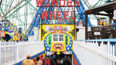 People walk towards the Wonder Wheel on the first day of the Coney Island parks reopening in the Coney Island neighborhood of Brooklyn borough on April 09, 2021 in New York City. Coney Island's Deno's Wonder Wheel Amusement Park and Luna Park opened today for the first time in 18 months after being closed due to the coronavirus (COVID-19) pandemic. Various government officials attended a ribbon-cutting ceremony to celebrate the reopening.